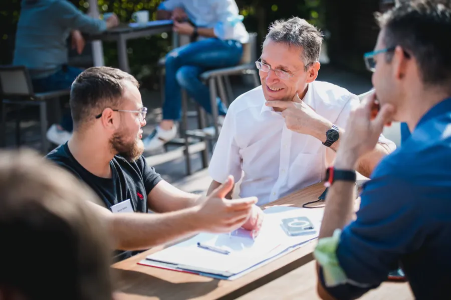 Stefan Merath im Gespräch mit Seminarteilnehmenden auf einer Terrasse